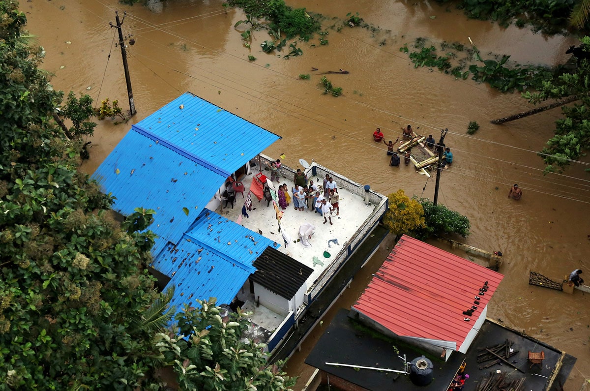 People wait for aid on the roof of their house